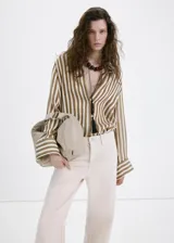 Jeans de algodón estilo wide leg en color beige, con diseño de tiro medio, cinco bolsillos, trabillas para cinturón y cierre frontal con botón y cremallera.