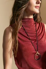 Top sin mangas de color negro con cuello alto y diseño drapeado en el frente. Confeccionado en una tela suave con acabado levemente satinado y silueta fluida.