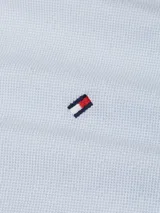 Chomba celeste de piqué con textura tipo diamante, cuello tipo chomba, tapeta de cinco botones y logo de Tommy Hilfiger bordado en el pecho.