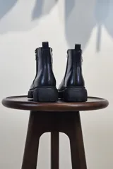 Bota de caña corta color marrón, con cierre lateral y suela track negra de goma con plataforma.