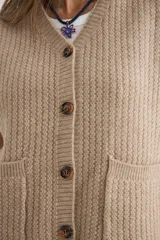 Chaleco de tejido de punto en color beige, con escote en V, cierre frontal con botones oscuros y dos bolsillos delanteros aplicados.