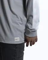 Remera de manga larga en color blanco, con cuello redondo y corte clásico. Presenta un pequeño detalle de etiqueta cosida en el puño de la manga.