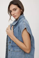Chaleco de jean negro de calce relajado, con cuello camisero, cierre frontal con botones metálicos y bolsillos delanteros con solapa.