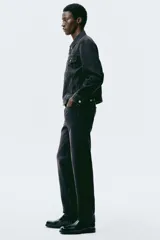 Jean de cinco bolsillos en denim de algodón rígido, color negro con efecto deslavado. Modelo con pierna recta y corte estándar de cintura a bajo, con cierre de botones.