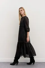 Vestido largo de tul negro con bordados de lentejuelas y canutillos, mangas tres cuartos abullonadas, cintura fruncida y falda con volado en el ruedo.