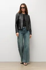 Chaqueta negra de cuero sintético, de manga larga, con detalle de pliegues en la parte frontal y cierre con cremallera.
