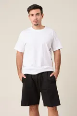 Bermuda de friza color negro, de corte suelto y largo por encima de la rodilla, con cintura elástica y cordón de ajuste.