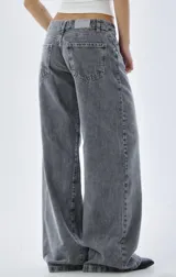 Pantalón de jean estilo wide leg, de tiro bajo, color gris lavado con efecto desgastado. Presenta corte recto y holgado en las piernas, con cierre frontal y bolsillos clásicos.