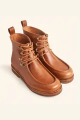 Bota de cuero vacuno color bordó con acabado charol, diseño de caña media con cordones y ganchos metálicos. Presenta costuras visibles en la puntera y suela de goma tipo crepe.