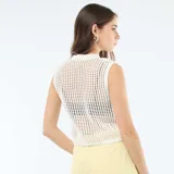 Top sin mangas de tejido crochet con cuello redondo y diseño de red, en color blanco.
