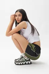 Short deportivo negro con detalles en verde militar, cintura elastizada, bolsillos laterales y ribete blanco.