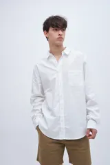 Camisa blanca de algodón, corte regular fit, con cuello solapa clásico, manga larga y bolsillo en el pecho.