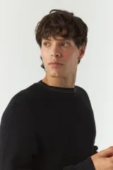 Sweater liso negro de algodón con cuello redondo y costuras a contratono.