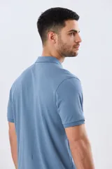 Remera polo de piqué de algodón color azul, de manga corta, con cuello camisero, cierre frontal de dos botones y pequeño logo bordado en el pecho.