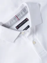 Chomba blanca de piqué de algodón elástico, corte slim, cuello de chomba, cartera de tres botones y logo de Tommy Hilfiger bordado en el pecho.