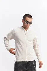 Campera tipo bomber color beige, con cierre frontal completo, cuello redondo y puños elásticos. Presenta una textura sutil en la tela y un calce cómodo.