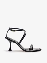 Sandalias negras de cuero vacuno satinado con tiras finas en la capellada, pulsera cruzada al tobillo con hebilla metálica dorada y taco fino de 7,5 cm.