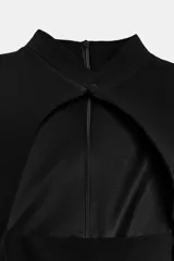 Vestido mini negro sin mangas, con cuello mao, abertura frontal tipo lágrima y forro interior a tono. Cierre en la espalda con cremallera oculta.