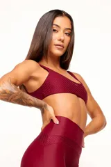 Top deportivo color verde oscuro, con tirantes finos y espalda descubierta. Diseño reversible con un lado brillante y otro con textura 3D tipo colmena.