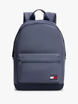 Mochila de diseño redondeado en color azul, confeccionada en poliéster. Cuenta con un compartimento principal con cierre de cremallera, un bolsillo exterior frontal con cierre, asa superior y correas acolchadas ajustables. Incluye parche distintivo de Tommy Jeans en la parte delantera.