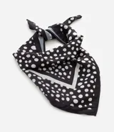 Pañuelo triangular de satén color negro con estampado de lunares blancos. Confeccionado en poliéster con acabado brillante y suave.