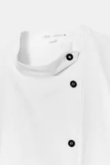 Camisa de popelín de algodón con cuello mao y cierre frontal asimétrico con botones a contraste. Presenta mangas cortas abullonadas y bajo recto.