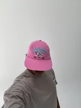 Gorro tipo béisbol color rosado con visera, bordado frontal con la palabra "AUTHENTIC" en azul y un perro dálmata en blanco y negro.