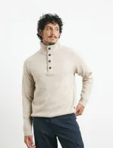 Sweater de punto color azul marino, con cuello alto, cierre frontal parcial y tapeta con botones. Presenta mangas raglán y puños y ruedo acanalados.