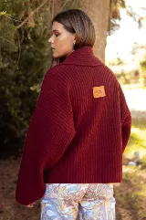 Saco de punto acanalado color bordó, con solapas anchas, cierre frontal cruzado con dos botones y mangas largas de corte holgado.