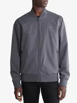 Campera bomber Calvin Klein color gris, confeccionada en poliéster resistente al agua con acabado mate. Cuenta con cuello redondo, cierre frontal completo, bolsillos laterales con cierre, logo en el pecho y ribete de punto acanalado.