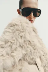 Chaqueta tipo bomber de textura afelpada en color crema, con cuello solapa, cierre frontal con cremallera y puños y cintura de tejido elástico acanalado.