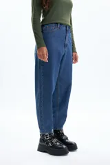 Jean de corte slouchy en color azul, con diseño de costuras visibles y cortes en las piernas. Presenta un tiro alto y una silueta holgada que se estrecha hacia los tobillos.