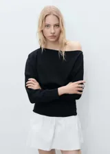 Vestido corto de diseño combinado con cuerpo negro de algodón y falda blanca con volante. Presenta cuello asimétrico, manga larga y cintura drapeada con ajuste entallado.