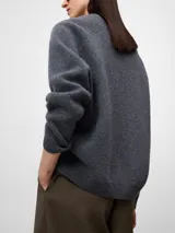 Jersey de lana gris melange con cuello en pico, manga larga y diseño de corte holgado con terminaciones en canalé en puños y ruedo.