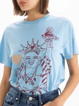 Remera celeste de jersey de algodón pima, con mangas cortas, escote redondo y silueta relajada. Cuenta con estampa frontal en serigrafía con relieve de Buda con elementos de la Estatua de la Libertad.
