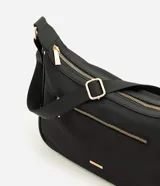 Cartera grande Satinato de color negro, confeccionada en poliéster con detalles en policloruro de vinilo. Posee un diseño moderno con cierre superior, bolsillo frontal con cierre visible y herrajes metálicos dorados, incluyendo una correa ajustable con hebillas y una placa con el logo de la marca.
