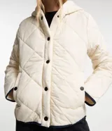 Campera de microfibra ligera color crudo, con textura capitoneada, capucha, cierre con botones a presión, mangas largas y puños con ribete en contraste.