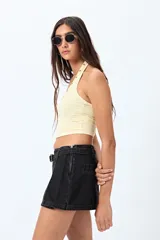Top halter color marrón, con escote redondeado y detalle de ojales metálicos a lo largo del cuello. Presenta un diseño ajustado al cuerpo y espalda descubierta.