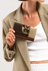 Billetera de cuero de diseño combinado en tonos chocolate, negro y champagne, con textura tipo animal print en el centro y placa metálica con el logo de la marca.