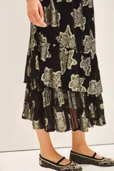 Falda larga de tiro alto con calce amplio, confeccionada en viscosa jacquard con detalles de lurex dorado. Presenta cintura elastizada con cordón de ajuste y volados irregulares en el ruedo. Incluye forrería a tono.