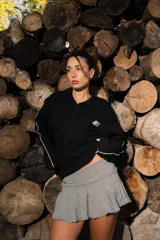 Buzo tipo polo de manga larga, color negro, con cuello y cierre parcial frontal. Presenta un pequeño bordado en el frente y la espalda.