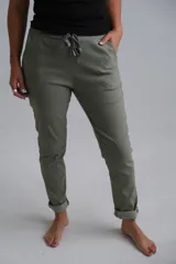 Pantalón de corte recto en color verde seco, confeccionado en tela elástica. Presenta cintura elástica con cordón ajustable y ruedos doblados.