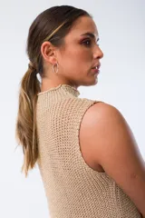 Vestido dorado de tejido de punto calado, con cuello alto y sin mangas.