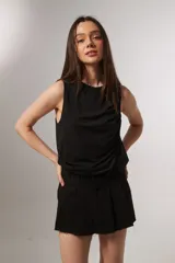 Musculosa negra sin mangas con cuello a la base y diseño holgado con frunces laterales.