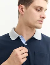 Remera manga corta color verde con cuello polo y bolsillo en el pecho. El cuello y los puños son de color azul marino.