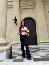 Buzo deportivo de corte holgado con diseño de rayas horizontales anchas en color marrón y rosado. Presenta cuello tipo polo con cierre frontal de botones y mangas largas con puños ajustados.