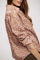 Camisa de manga larga con cuello camisero y cierre frontal de botones. Presenta un estampado de puntos irregulares en tonos tierra.