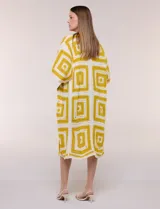 Cardigan largo confeccionado en tejido de punto calado estilo crochet, de color amarillo y blanco, con diseño geométrico de cuadrados, mangas amplias tipo kimono y corte abierto al frente.