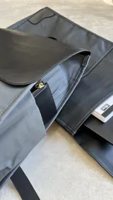Mochila negra de cuero sintético con solapa superior y cierre con hebilla.