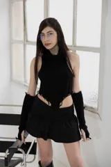 Top negro de tejido de punto con cuello alto, corte irregular y detalle de flecos deshilachados. Incluye guantes largos sin dedos.